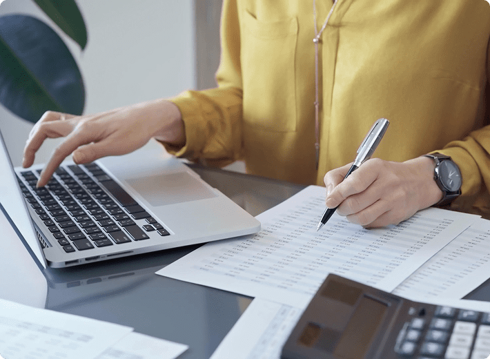 Person working on laptop and documents.