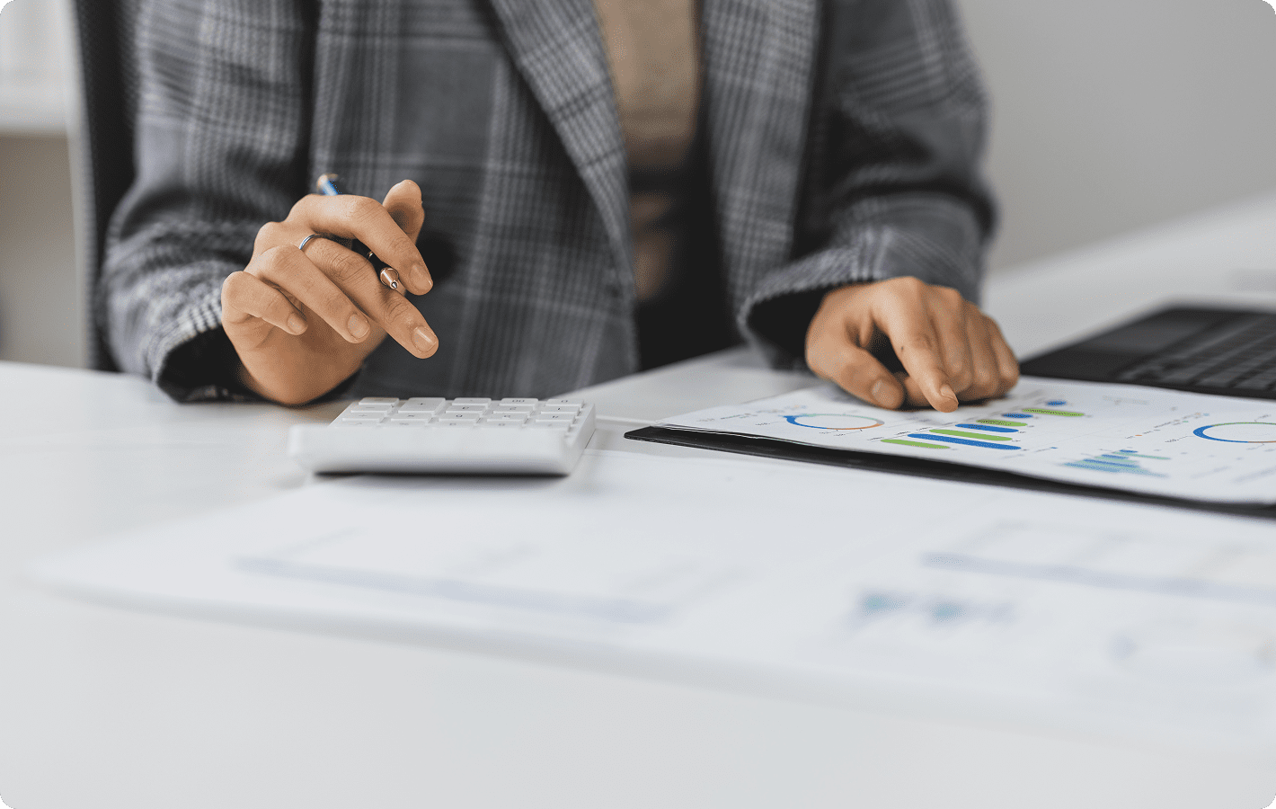 Person calculating with charts and calculator.